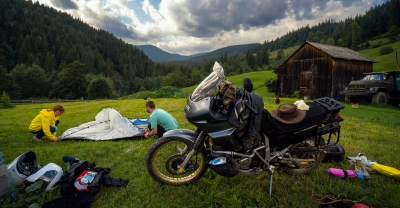 Couple setting up a tent near parked motorcycle