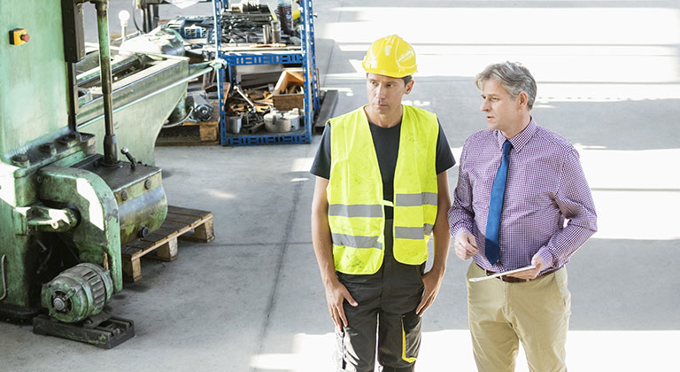 Business man consulting factory worker in hard hat