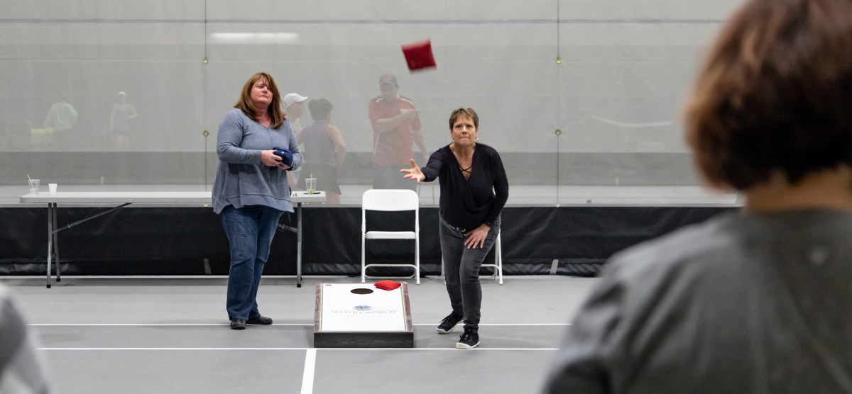 carousel-corporate-event-team-building-4-1200x556 Two people playing cornhole in the SentryWorld Fieldhouse.