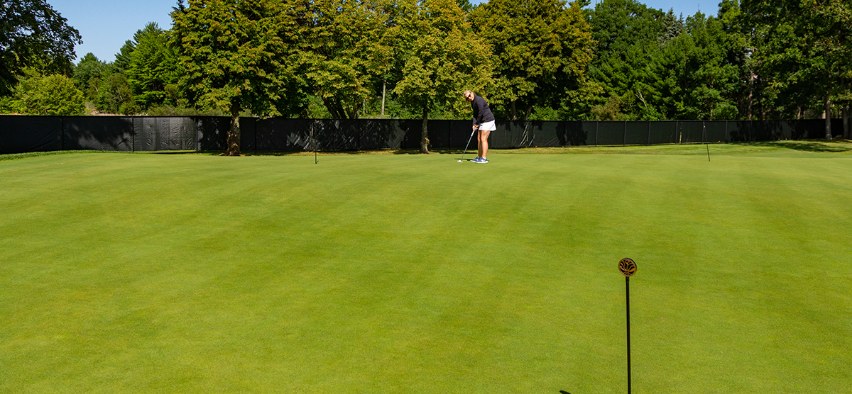 Woman putting on the practice green at SentryWorld