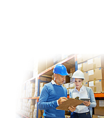 Two business professionals wearing safety helmets in a warehouse