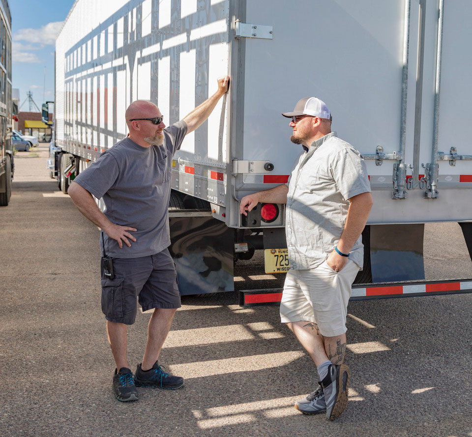 Two men talking near a semi-truck