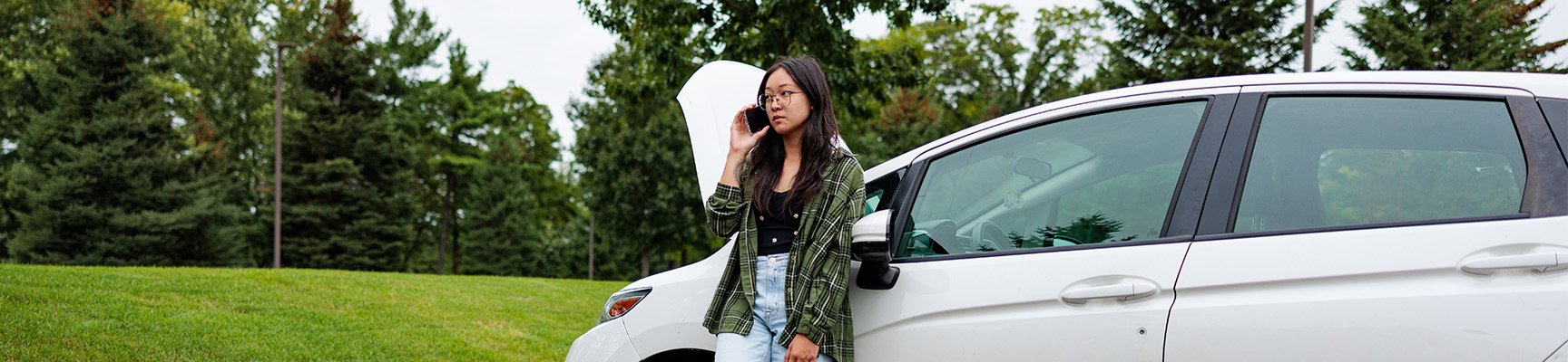 Young woman making a call after experiencing car trouble.