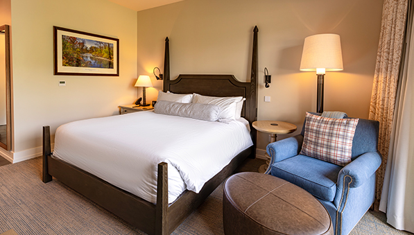 Room with a king size bed, chair, and ottoman.