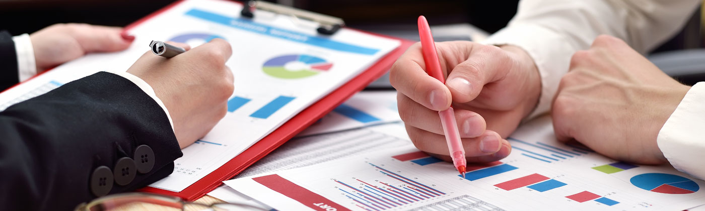 Two people reviewing paper graphs and reports