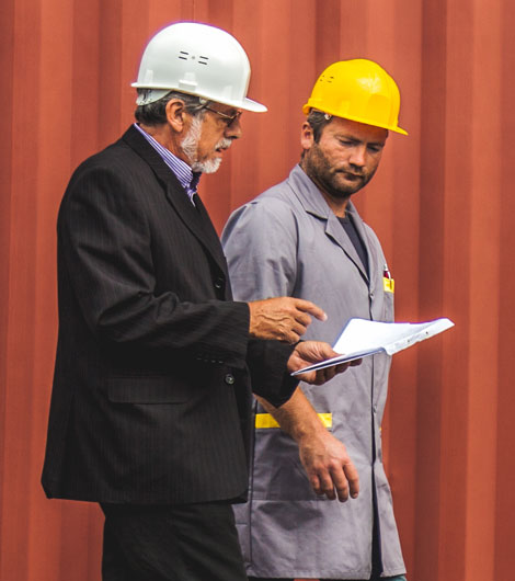 Person in suit and hard hard with worker in hard hat talking.