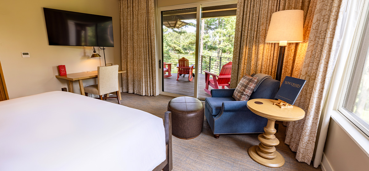 carousel-executive-golf-view-king-terrace-4-1200x556 King bed with seating area, desk, and patio door overlooking the golf course.