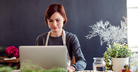 Woman using a laptop at a desk with plants