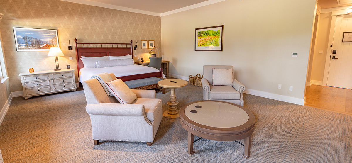 carousel-accessible-golf-view-executive-junior-suite-3-1200x556 King bed with two chairs, coffee table and a desk.