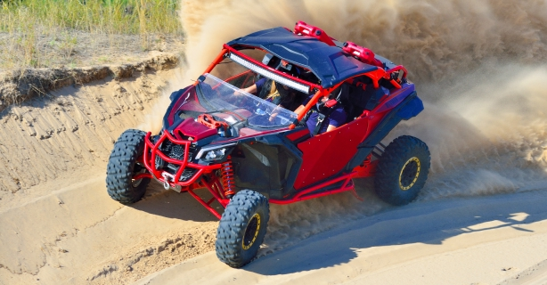 Red ATV driving on a sandy trail.
