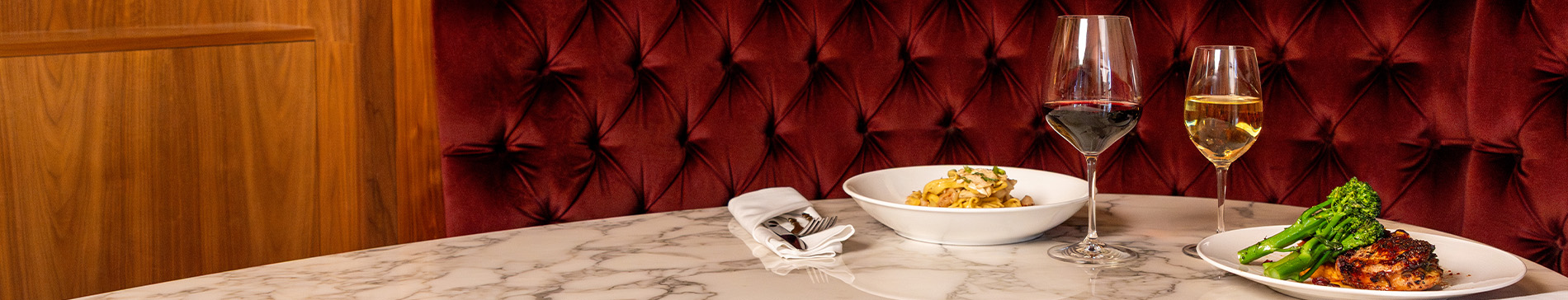 Bowl of pasta with red wine and plate of chicken with white wine. 