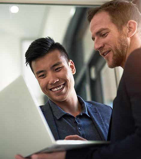 Two people smiling and looking at laptop