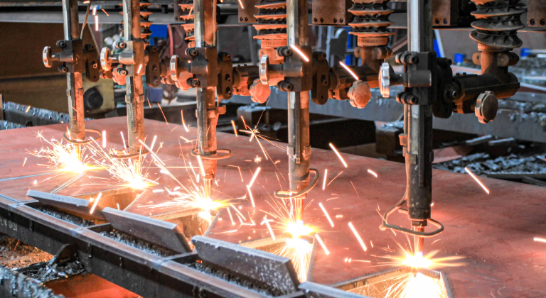 Multiple cutting torches cutting metal with sparks flying.