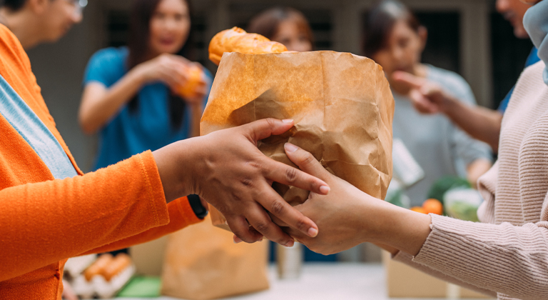 Close up of hands handing over a bag of food from one person to another