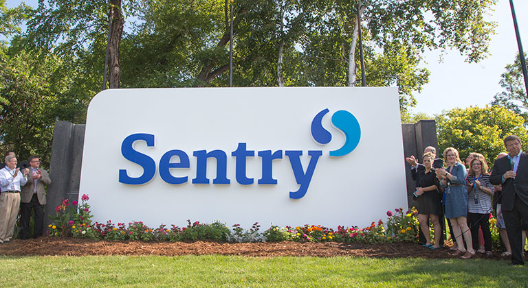 Sentry employees standing by Sentry sign