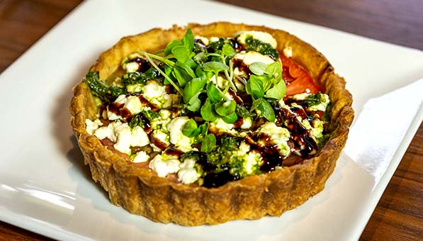 Warm Heirloom Tomato Tartlet plated on a table at Muse