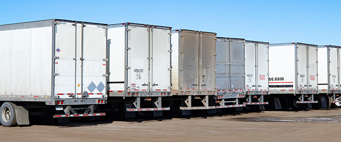 White semi trailer trucks from behind parked in a line