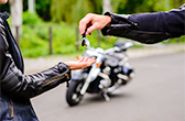 A person handing the keys to a motorcycle to another person