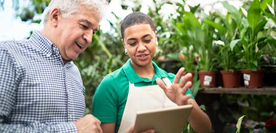 Two people looking at a piece of paper with plants in the background