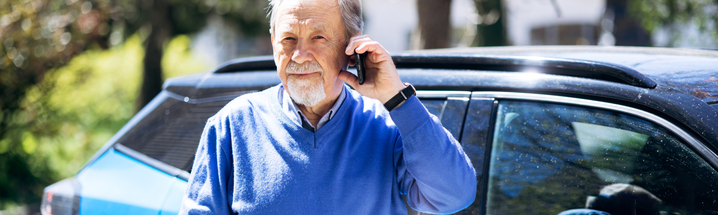 Man stands next to vehicle while on phone.