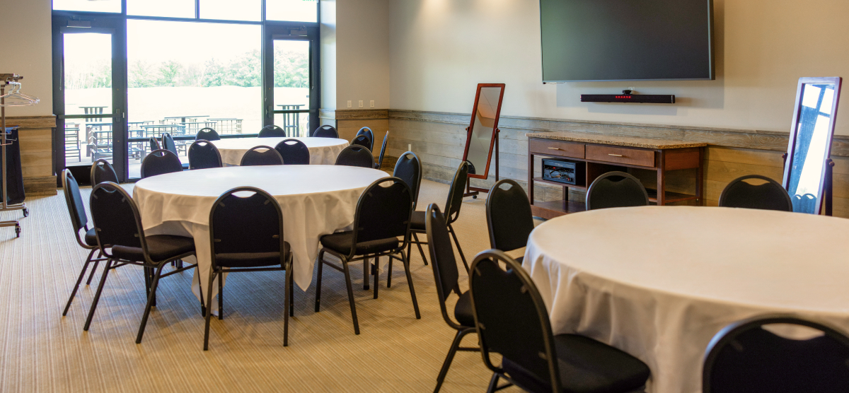 Three round tables with chairs and mirrors for getting ready and door to an outdoor patio. 