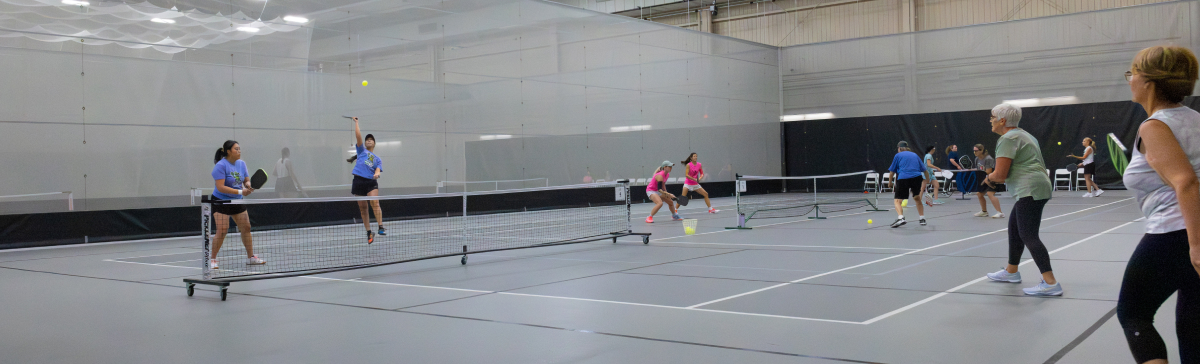 SentryWorld fieldhouse with multiple pickleball games being played. 