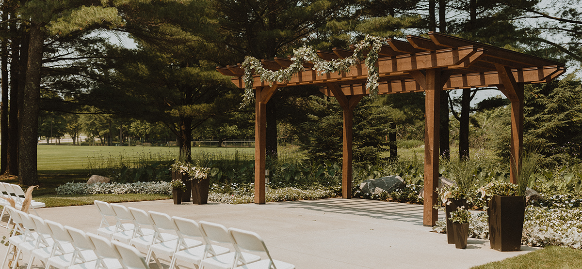 Chairs and greenery hung on the outdoor pergola at SentryWorld