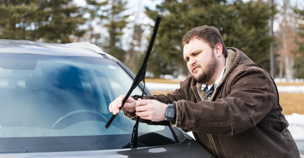 Inspecting windshield wipers on car