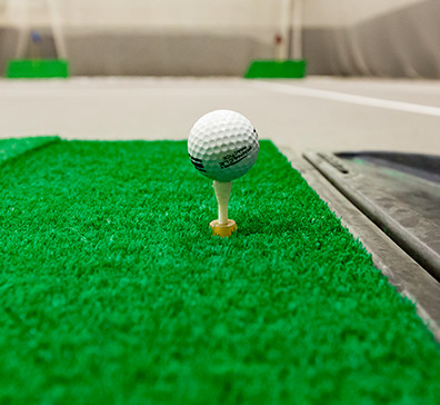 Golf ball on a tee on a practice mat in the fieldhouse at SentryWorld