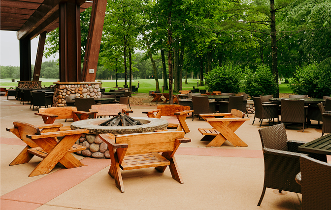Outdoor patio with a fire pit, various seating, and a golf course in the background.