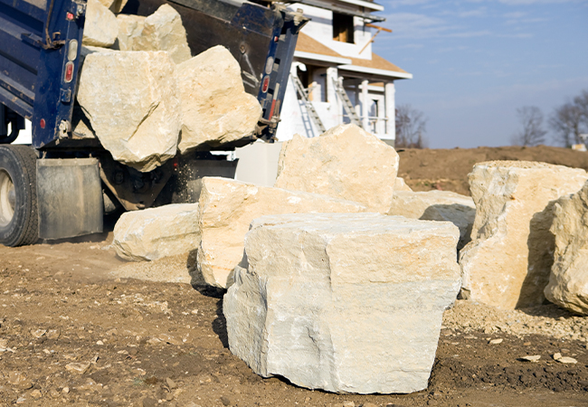 Truck unloading large boulders