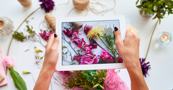 Someone taking a picture of flowers with a tablet