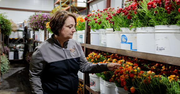 woman overlooking buckets of cut flowers in storage cooler