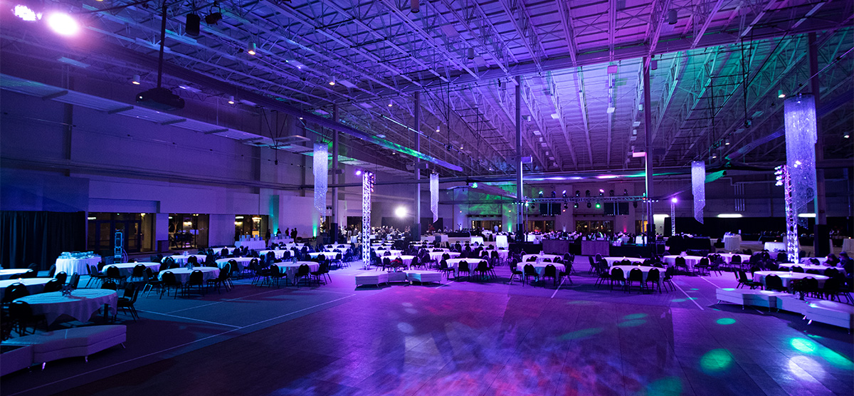 Dance floor with colorful lighting and tables for an event in the fieldhouse at SentryWorld