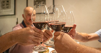 Four friends clinking glasses of red wine while seated at a table in Muse.