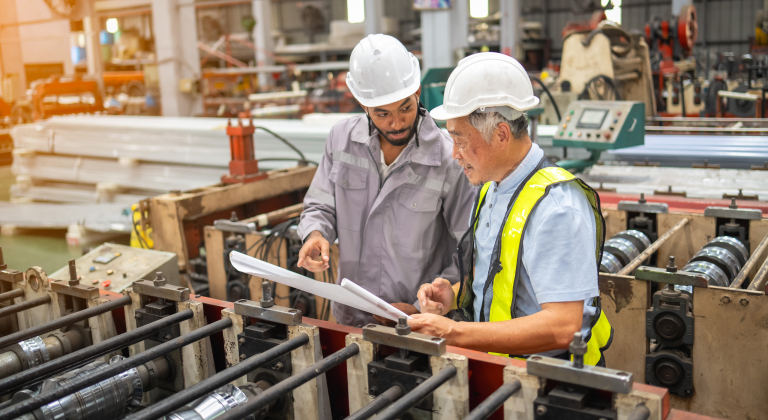 Two manufacture workers overlooking paperwork.