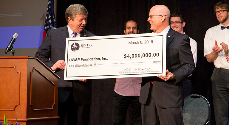 Pete McPartland gives donation check to University of Wisconsin-Stevens Point representative