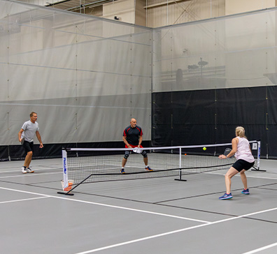 Three people playing pickleball in the SentryWorld fieldhouse