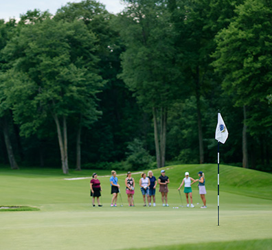 Group of women during a golf lesson standing on a green and listening