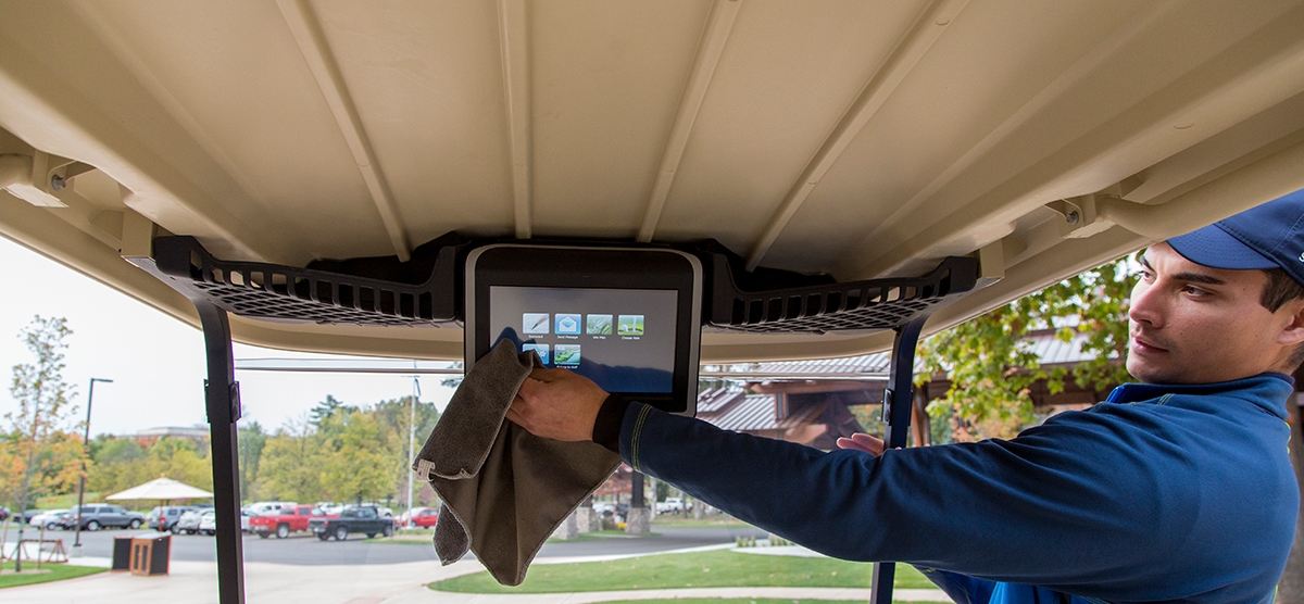 Employee cleaning the screen attached to a SentryWorld golf cart