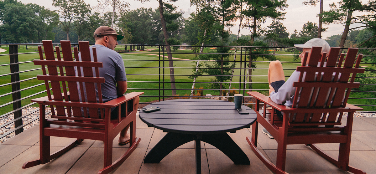Two men sitting on the executive lounge balcony in rocking chairs. 