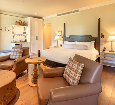 image-card-package-vip-comedy-396x364 Room with a king size bed, two chairs, end table, and coffee area.