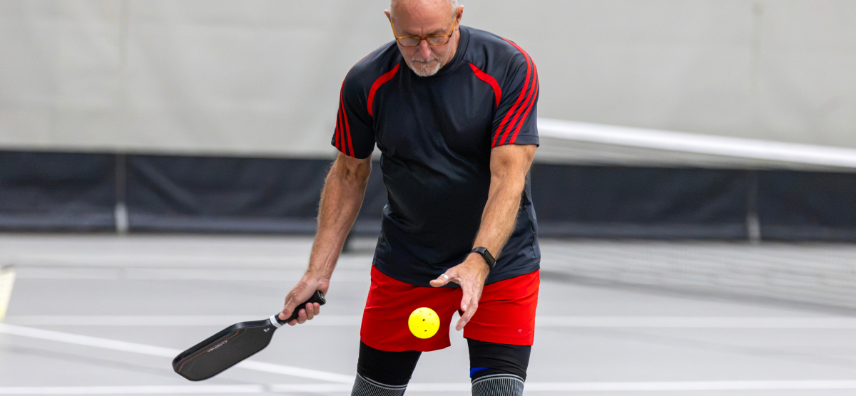 Male pickleball players readies a serve.