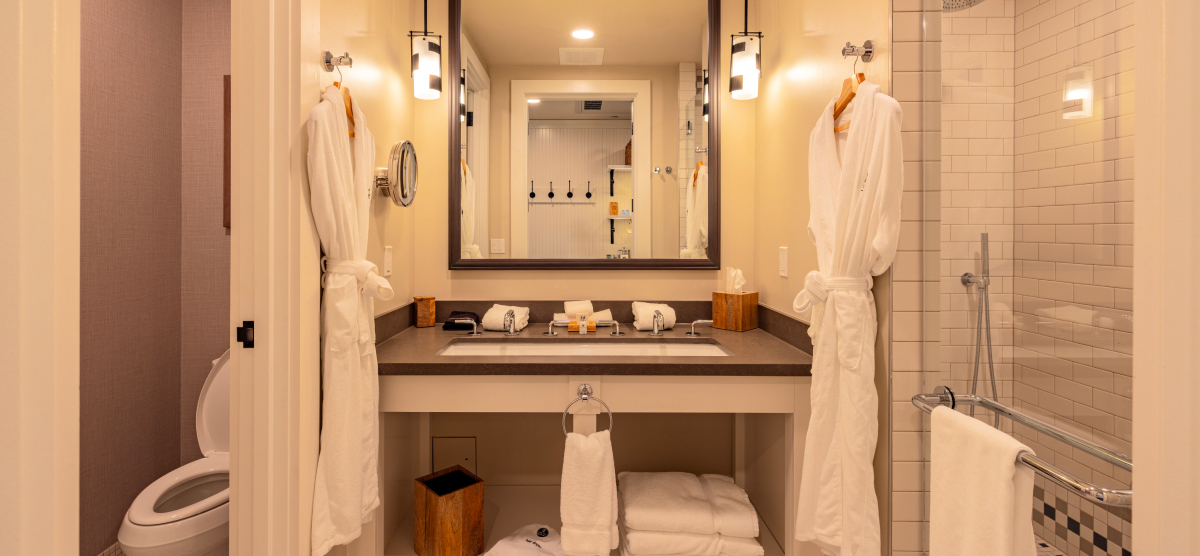 Bathroom sink area with two white robes. 