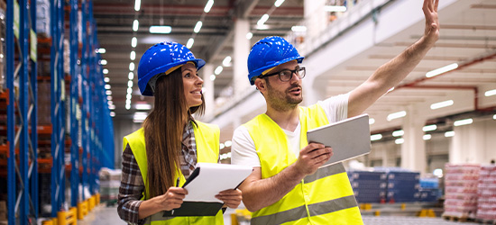 Two people in high visibility vests with hard hats