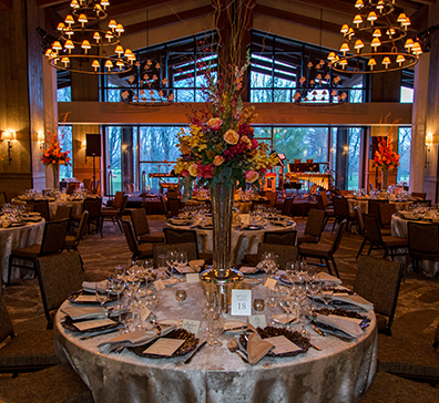 Round tables with floral center pieces and table settings for a wedding reception in the Grand Hall