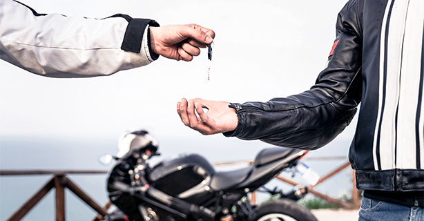 Man giving keys to motorcycle to another man