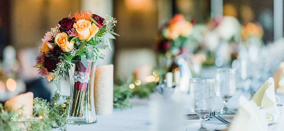 Flower bouquets and greenery along a table for a wedding reception