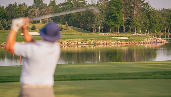 Man watching his golf ball after hitting it across water. 