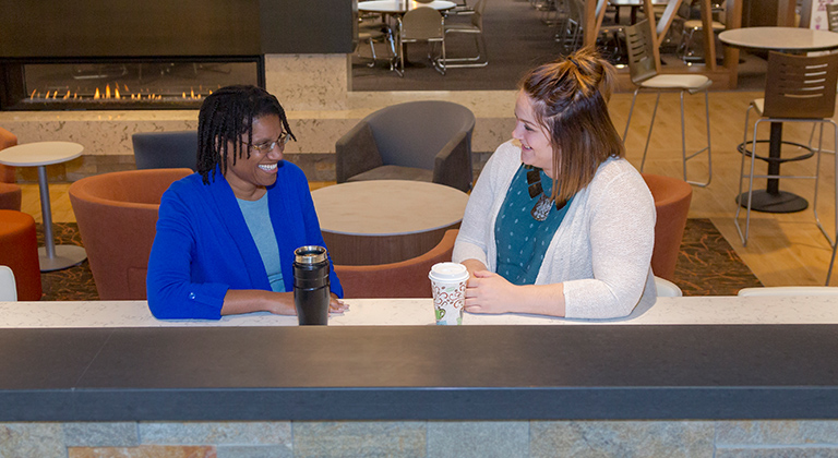 Two people sitting in the Sentry cafeteria drinking coffee